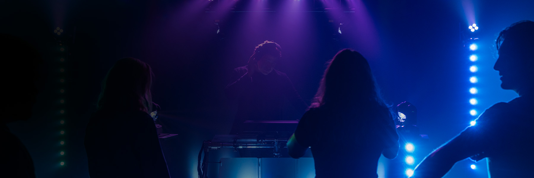 2 People Partying In Front Of The Dj With Lighting Effect On Stage